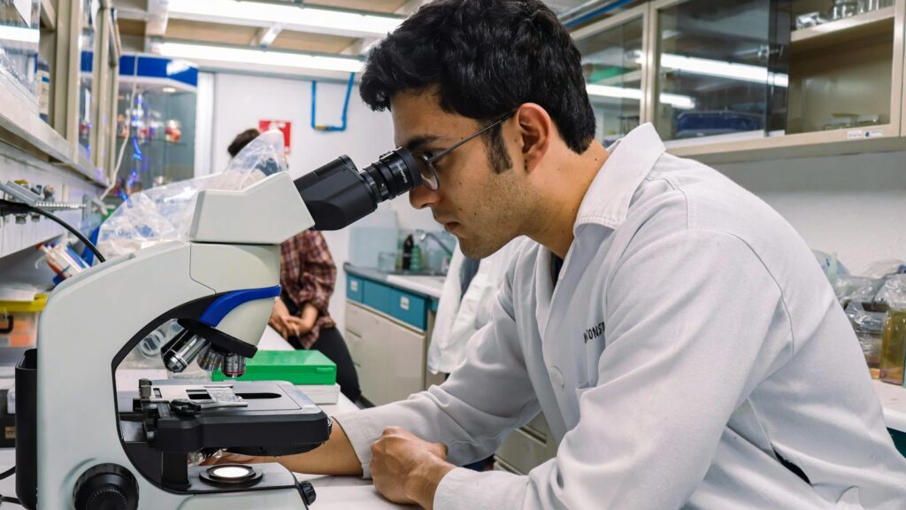Scientist examining samples under a microscope in a modern laboratory.