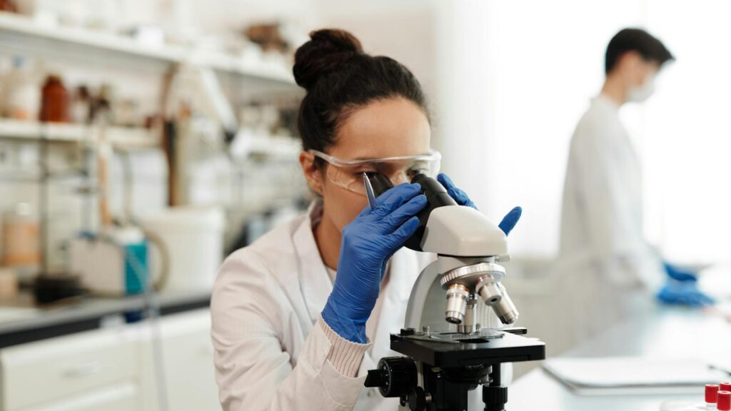 Scientist examining a sample through a microscope in a laboratory.