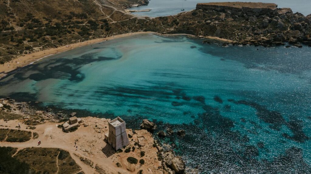 Aerial view of Golden Bay in Mellieha, Malta, showcasing the stunning blue waters and rugged coastline.