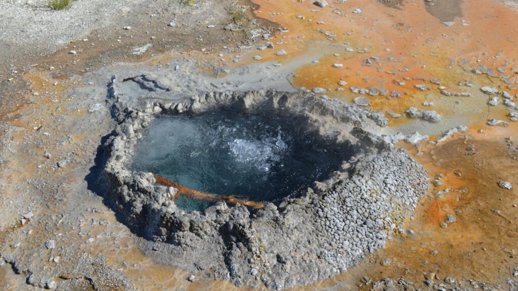 A bubbling geyser at Yellowstone National Park showcasing colorful geothermal features.