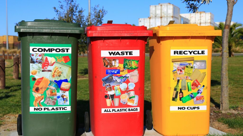 Three color-coded bins labeled Compost, Waste, and Recycle in a park.