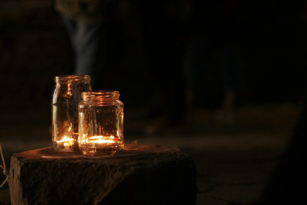 Fireflies settled at the bottom of glass bottles, their faint glow casting soft light through the glass.