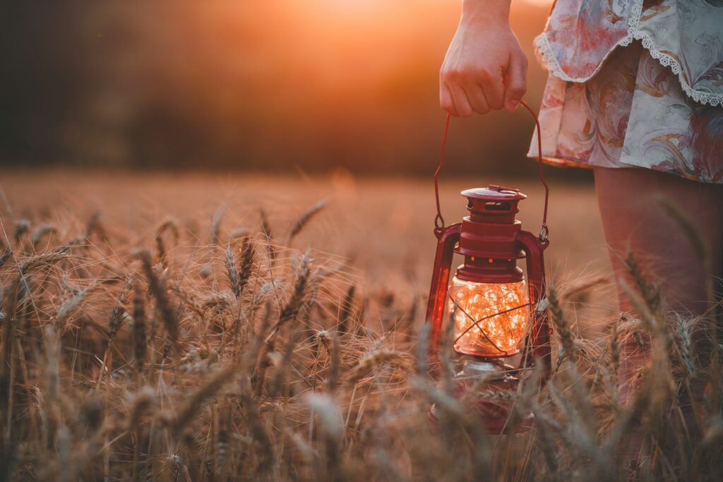 A woman holding a glass lamp glowing with fireflies.