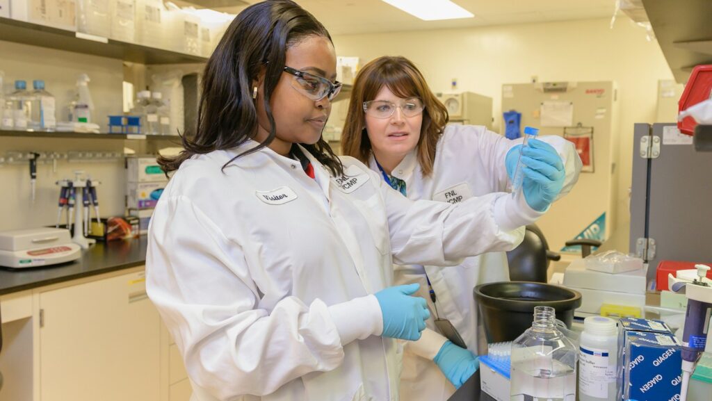two women in lab coats working in a lab