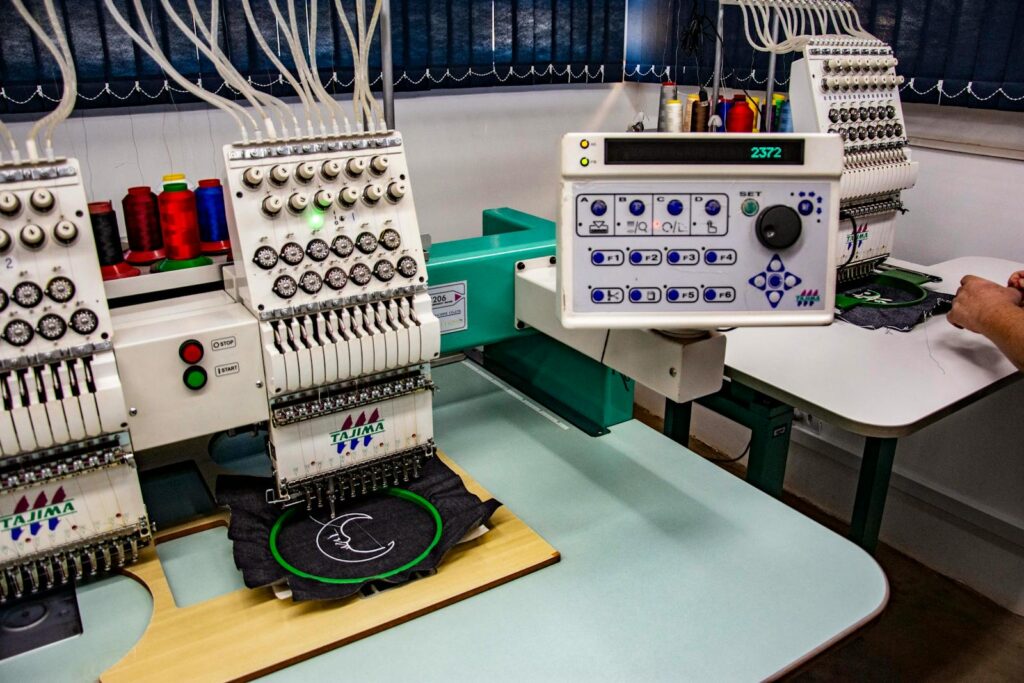 Detailed view of embroidery machines used in a textile workshop in Apucarana, Brazil.