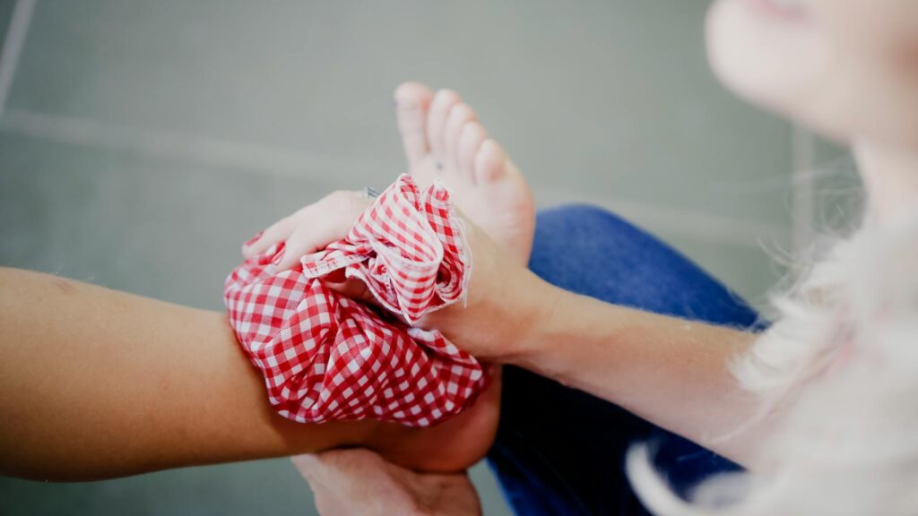 Close-up of a person using a checkered ice pack on an injured ankle, promoting injury care and relief.