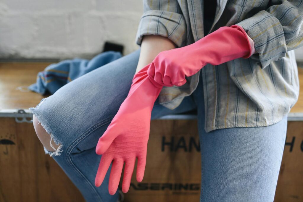 A person wears pink rubber gloves indoors
