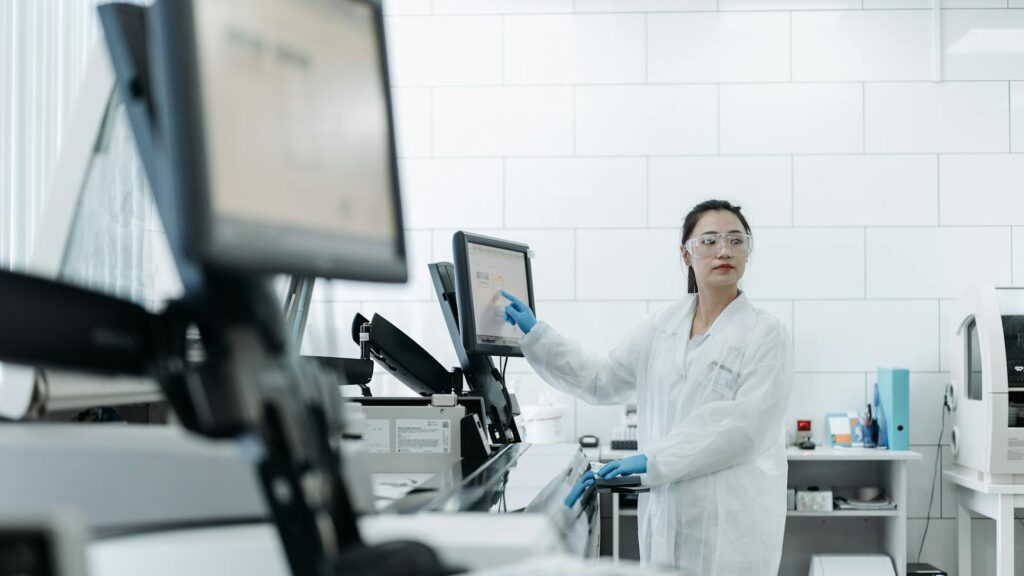 Lab technician in a white coat using medical equipment in a modern laboratory setting.