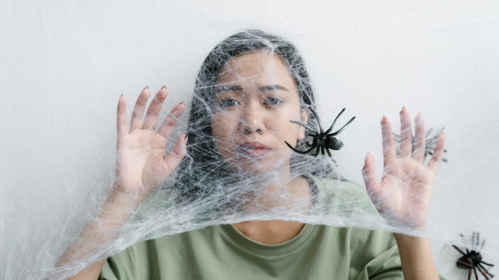 A woman caught in a web of fear, illustrating anxiety and entrapment with a spider.