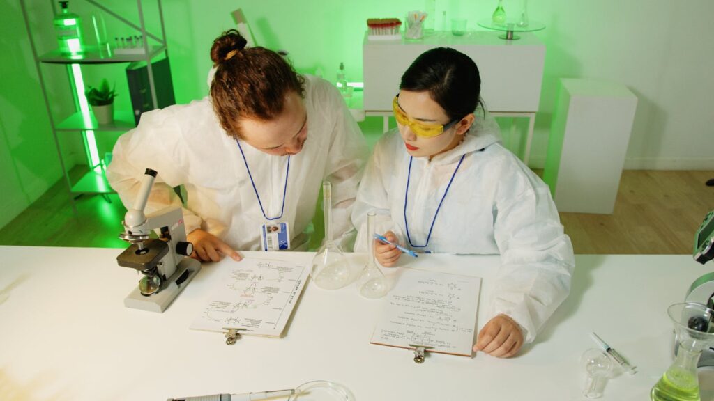 Two scientists in protective gear discussing experiments in a modern laboratory.