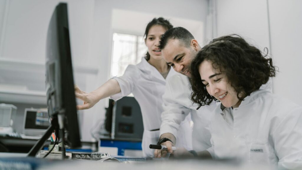 Group of diverse scientists working together on a computer in a bright, modern laboratory.