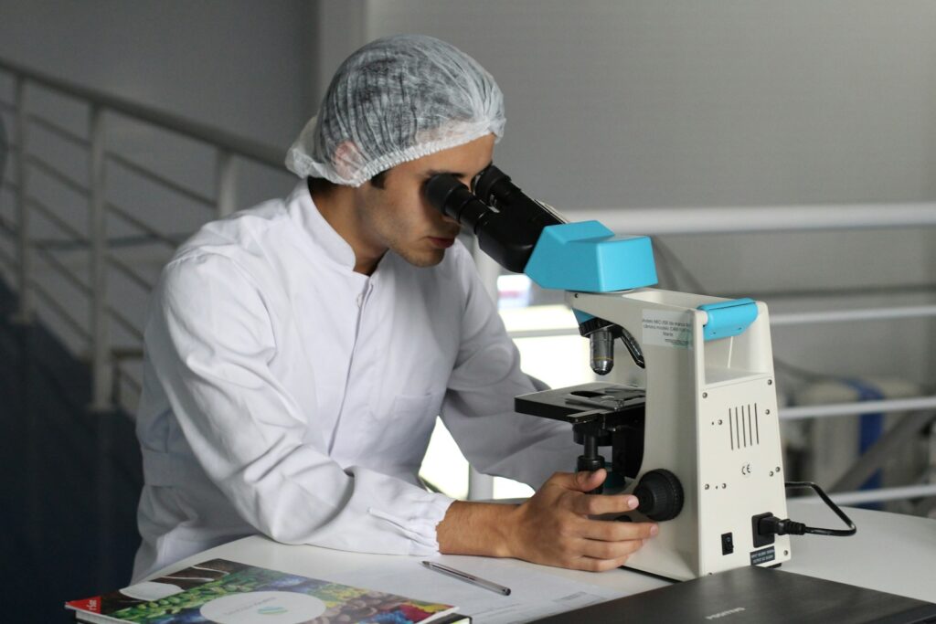 Man looking through a white microscope