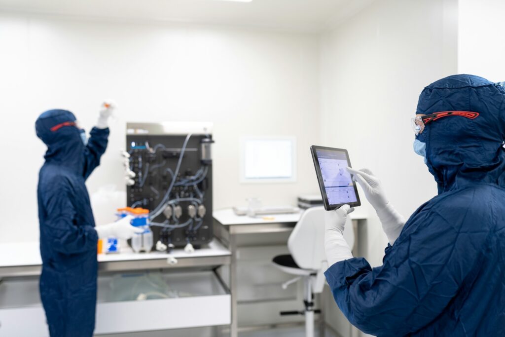 A couple of people in blue protective gear in front of a computer