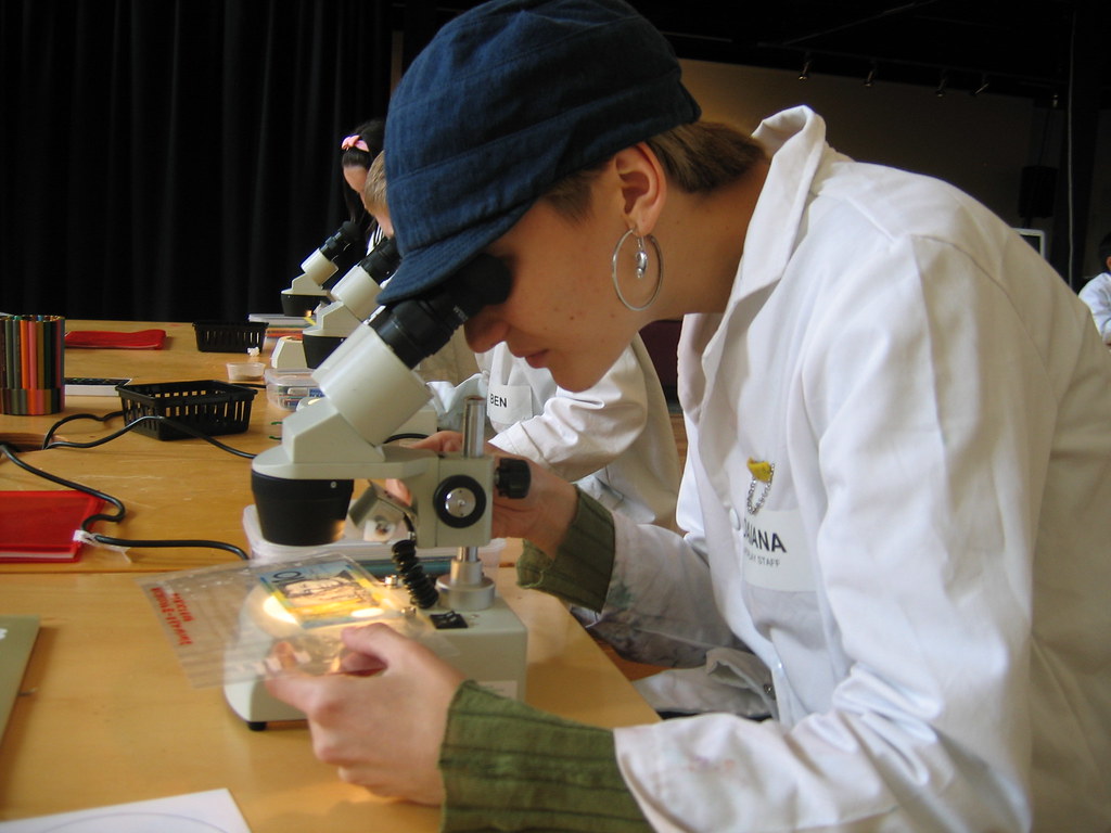 A woman looking at a $10 note under the stereo microscope