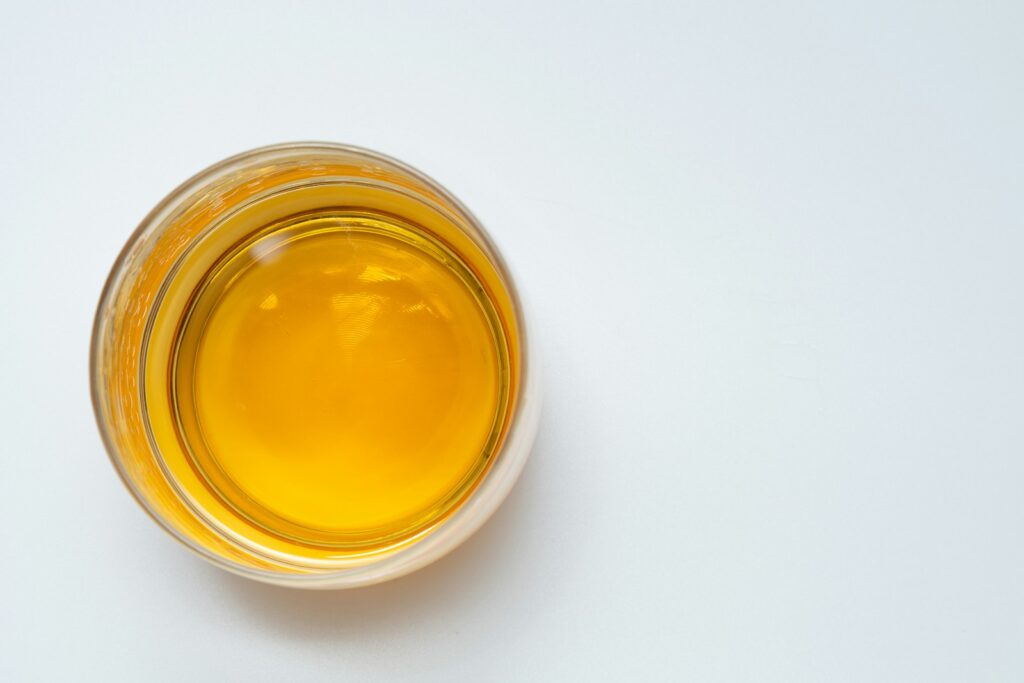 A glass filled with oil sitting on top of a white table