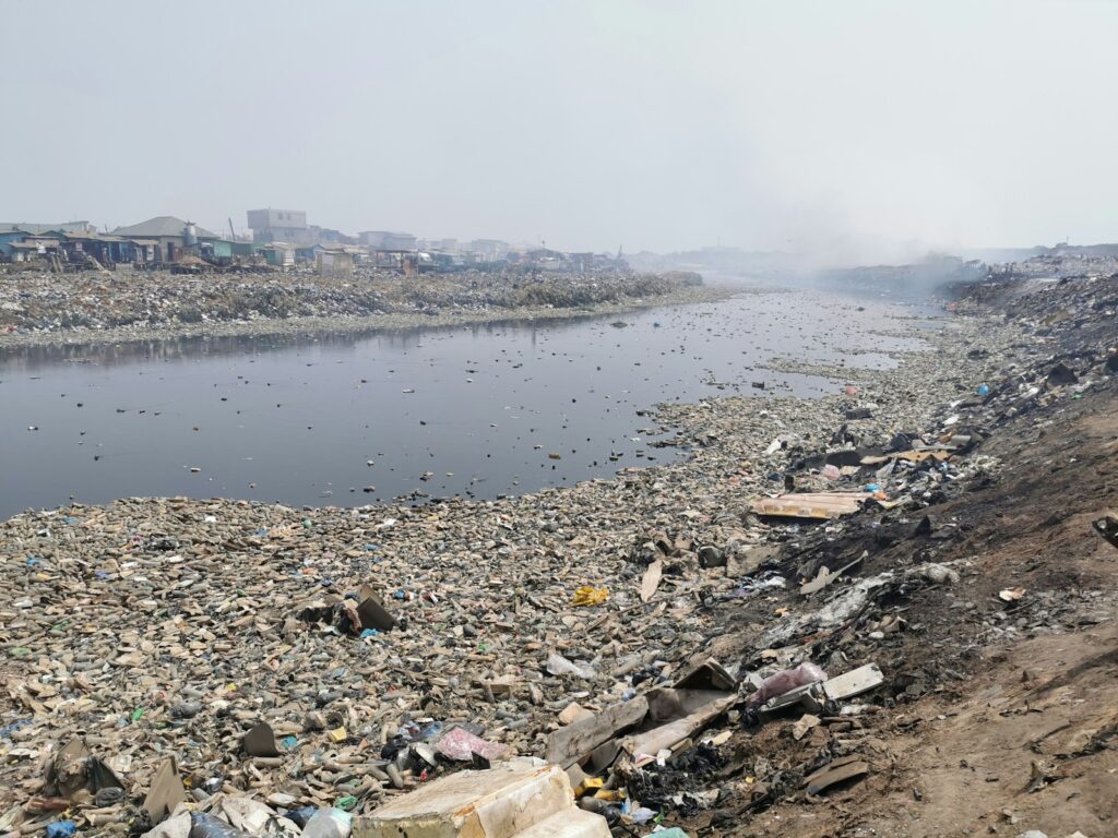 A large amount of trash is on the shore of a river