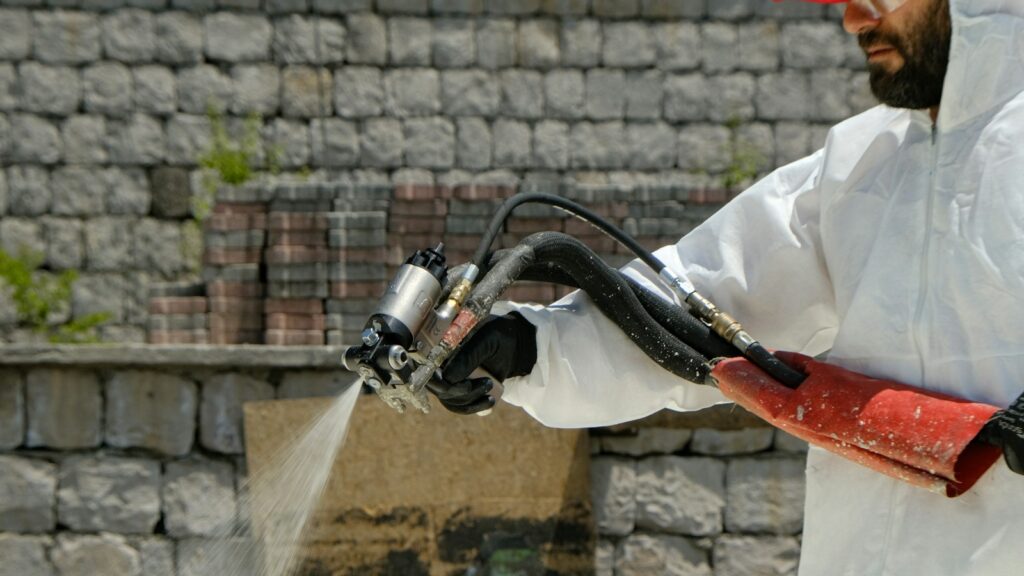 a man in a white coverall spraying water with a hose