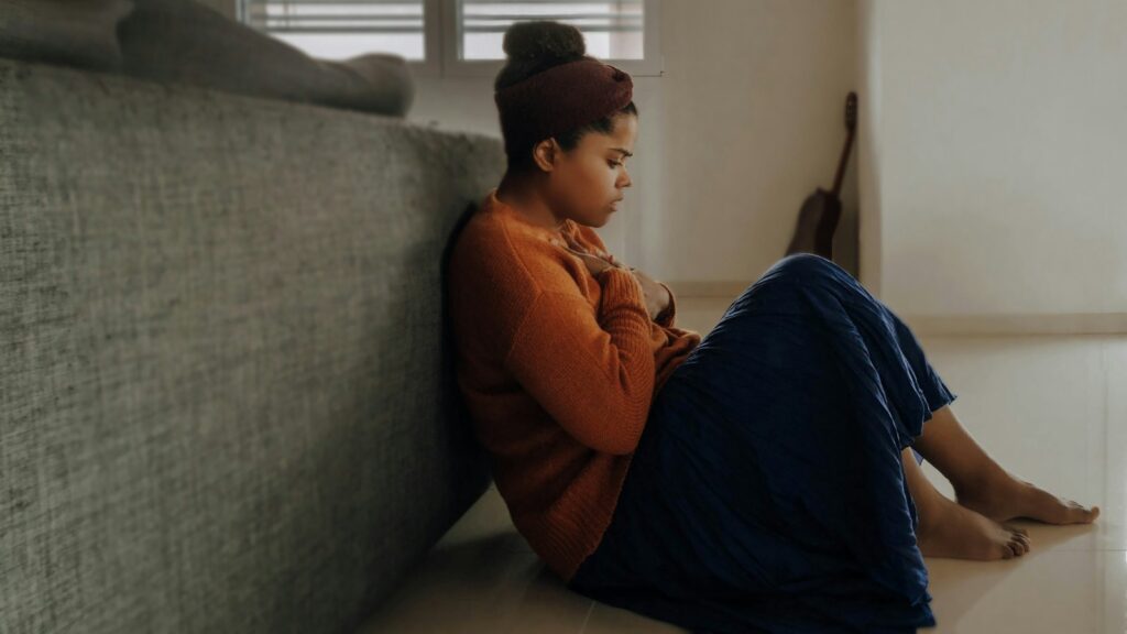 man in orange long sleeve shirt sitting on gray couch