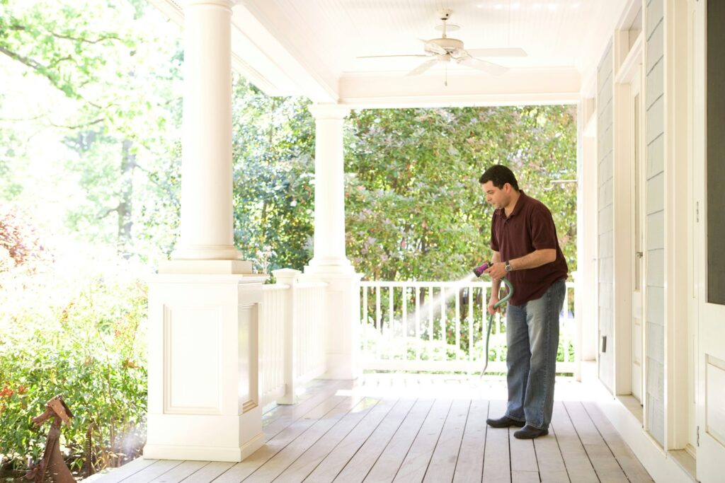 Man in brown t-shirt and blue denim jeans spraying insecticide