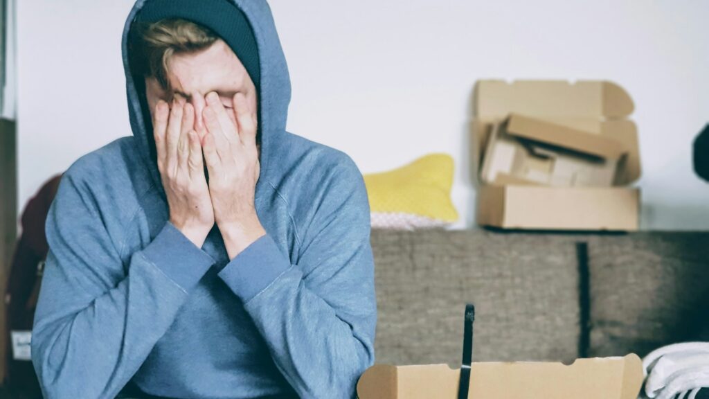 man covering face with both hands while sitting on bench