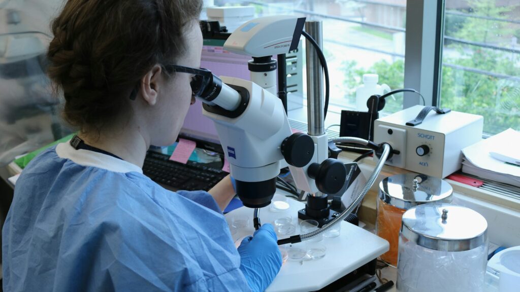a woman in a lab coat looking through a microscope