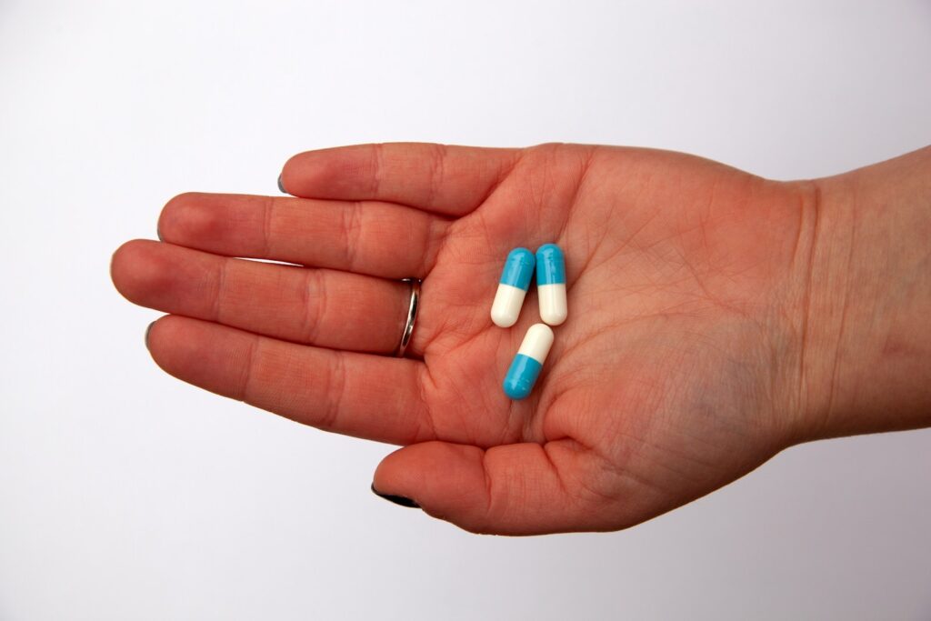 Three capsules on a person's palm